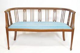 An Edwardian mahogany salon sofa with curved back rail,