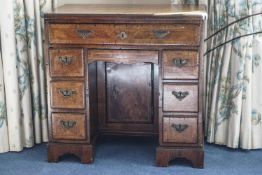 A George III walnut and cross banded kneehole bureau with an arrangement of seven drawers