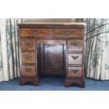 A George III walnut and cross banded kneehole bureau with an arrangement of seven drawers
