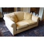 A two seat sofa upholstered in yellow on oak bun feet,