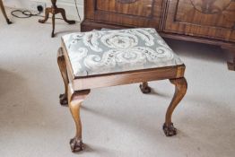 A mahogany stool with drop in seat, on carved cabriole legs, with ball and claw feet,