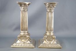 A pair of silver Corinthian candlesticks, of loaded form,