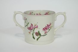 A late 19th century bone china loving cup, decorated with flowering honeysuckle motifs,