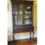 An Edwardian mahogany display cabinet with two glazed doors above two drawers