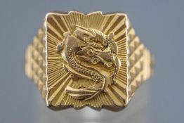 A yellow metal rectangular signet ring depicting a Chinese dragon.