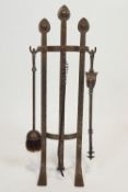 A wrought iron set of three fire irons on stand in Art Nouveau style,