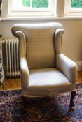 An early 20th century wing armchair on cabriole legs with additional casters