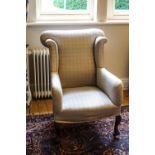 An early 20th century wing armchair on cabriole legs with additional casters