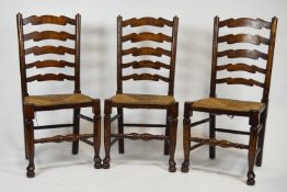 A set of six elm wood traditional form ladder back chairs with rush seats and baluster turned legs
