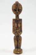 An African hardwood Fetish figure, depicting a standing female in a bead collar holding a pot,