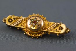 A yellow metal filigree design hollow bar brooch having a central cluster set with paste stone and