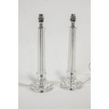 A pair of cut glass table lamps, of column form, on flared bases,