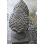 A pair of composite stone pine cone finial ornaments raised on square socles,