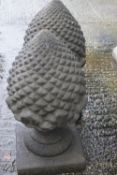 A pair of composite stone pine cone finial ornaments raised on square socles,