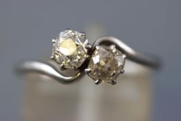 A white metal crossover ring set with two old European cut diamonds.