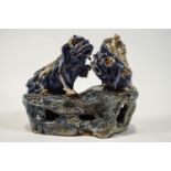 A 19th century Chinese earthenware figure of two Dogs of Fo playing on a rocky base,