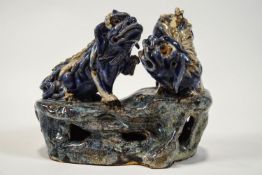 A 19th century Chinese earthenware figure of two Dogs of Fo playing on a rocky base,