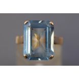 A yellow metal single stone ring. Set with a rectangular faceted cut blue synthetic spinel.