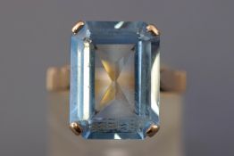 A yellow metal single stone ring. Set with a rectangular faceted cut blue synthetic spinel.