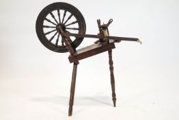 A late 19th century spinning wheel, on three turned tapering legs,