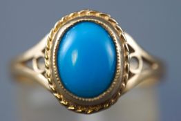 A yellow metal single stone ring. Set with an oval cabochon cut turquoise. Hallmarked 9ct gold.