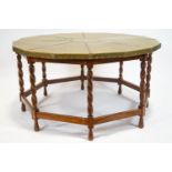 A coffee table with a brass hexadecagon top on an oak frame with barley twist legs linked by