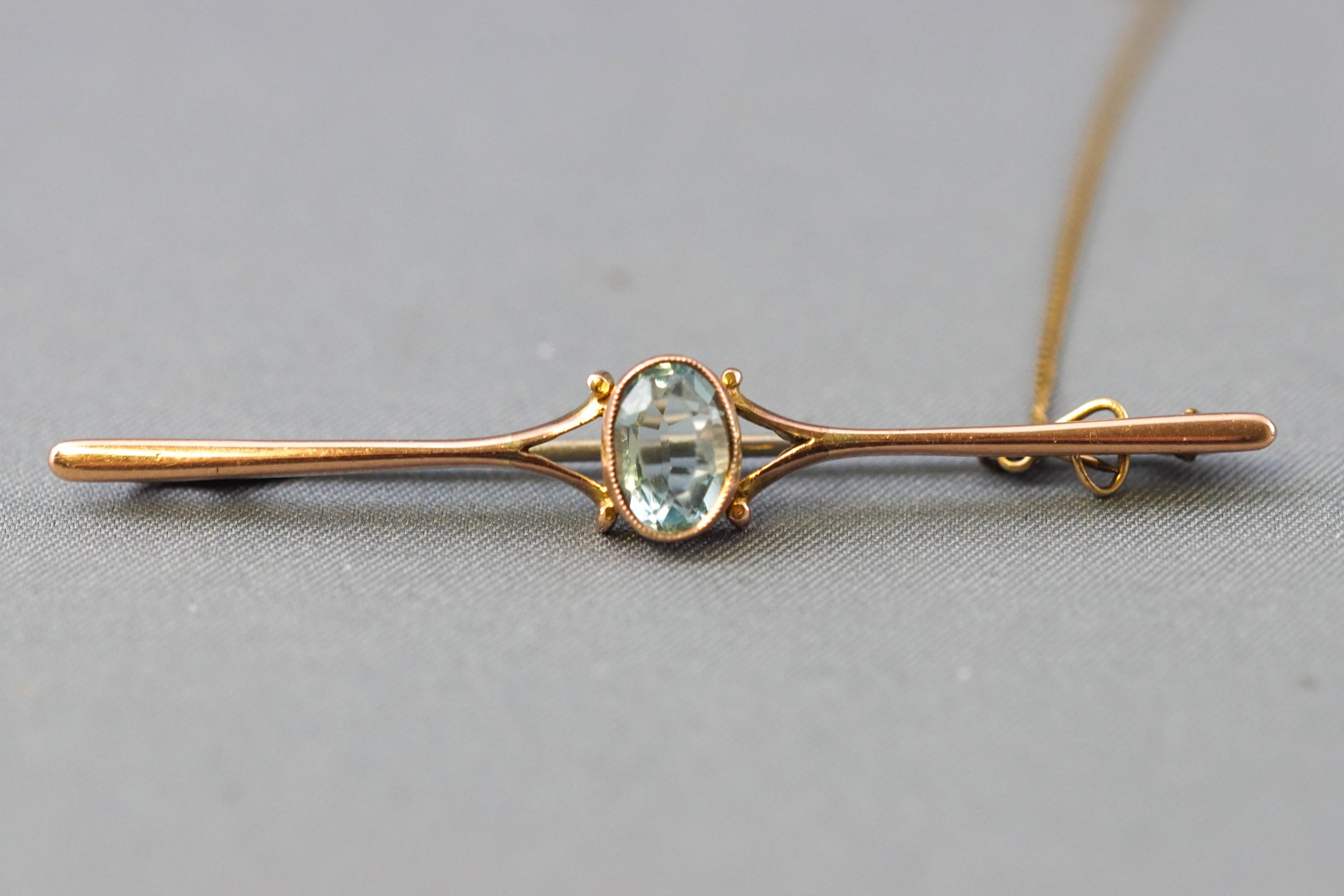 A yellow metal bar brooch centrally set with an oval faceted cut aquamarine.