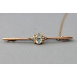 A yellow metal bar brooch centrally set with an oval faceted cut aquamarine.