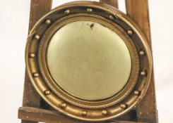 A Regency style gilt framed convex circular mirror, the frame embellished with ball finials,