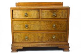 An Edwardian walnut chest of two short and two long drawers with brass ring handles and ogee