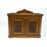 An oak aesthetic movement hanging corner cupboard with crenellated top set over two panel doors,