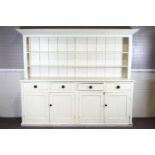 A white painted pine dresser, with four shallow drawers above two sets of twin cupboard doors,
