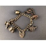 A white metal curb link bracelet having three fixed charms and three loose charms.