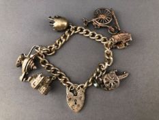 A white metal curb link bracelet having three fixed charms and three loose charms.