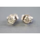 A white metal pair of single stone stud earrings each set with a round brilliant cut diamond
