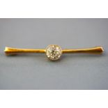 A yellow metal bar brooch centrally set with a colourless round faceted cut zircon measuring