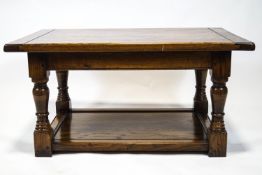 A period style elm coffee table with a three plank style top raised on turned legs on a solid base