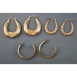 A collection of three pairs of yellow metal hollow hoop earrings.