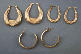 A collection of three pairs of yellow metal hollow hoop earrings.