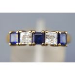 A yellow metal half hoop ring. Set with synthetic blue sapphire and colourless cubic zirconia.