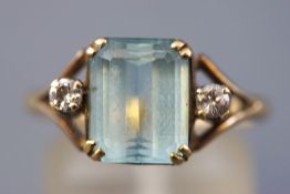 A yellow metal three stone ring principally set with a rectangular cut aquamarine estimated to