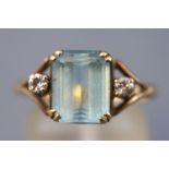 A yellow metal three stone ring principally set with a rectangular cut aquamarine estimated to