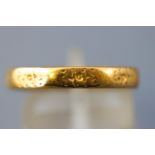 A yellow metal court shaped wedding ring with engraved design. Hallmarked 22ct gold, London.