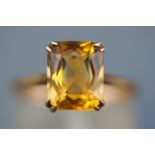 A yellow metal single stone ring set with a rectangular faceted cut citrine quartz.