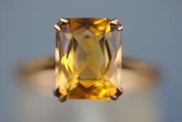 A yellow metal single stone ring set with a rectangular faceted cut citrine quartz.