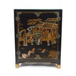 A Chinoisere two door cabinet decorated with figures in landscapes on a black ground,