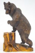 A Black Forest carved wood figure of a bear on his hind legs, resting one paw on a stump, 26.