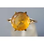 A yellow metal single stone ring set with a circular faceted cut citrine quartz measuring