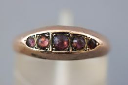 A rose metal half hoop ring set with five circular cabochon cut purple stones (Too worn to test