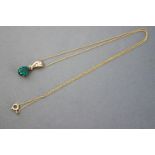 A yellow metal created (synthetic) emerald and diamond pendant suspended from a fine trace link